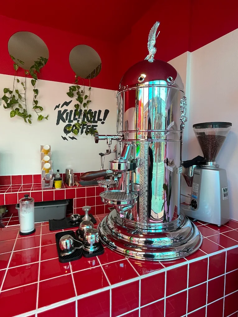 The shop’s gleaming chrome espresso machine surrounded by red tiles and hanging plants